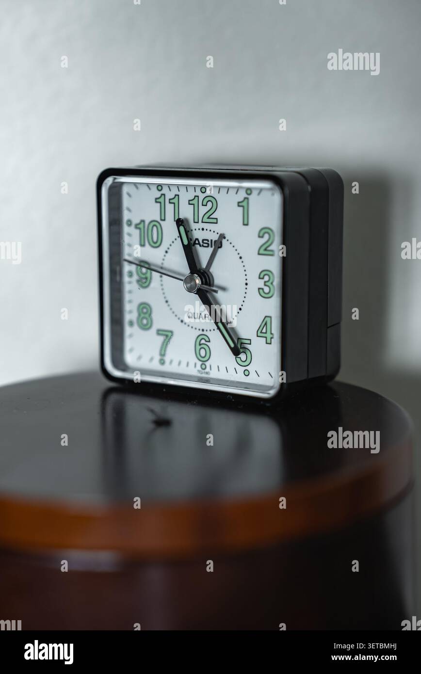 CASIO quadratischer Wecker auf poliertem hölzernem Nachttisch um 10 Uhr Stockfoto