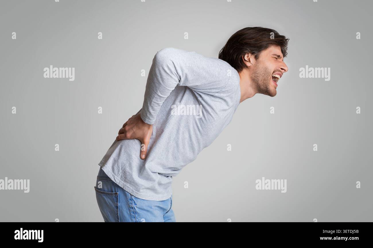 Junger Mann schreit vor Schmerzen in seinem Rücken Stockfoto