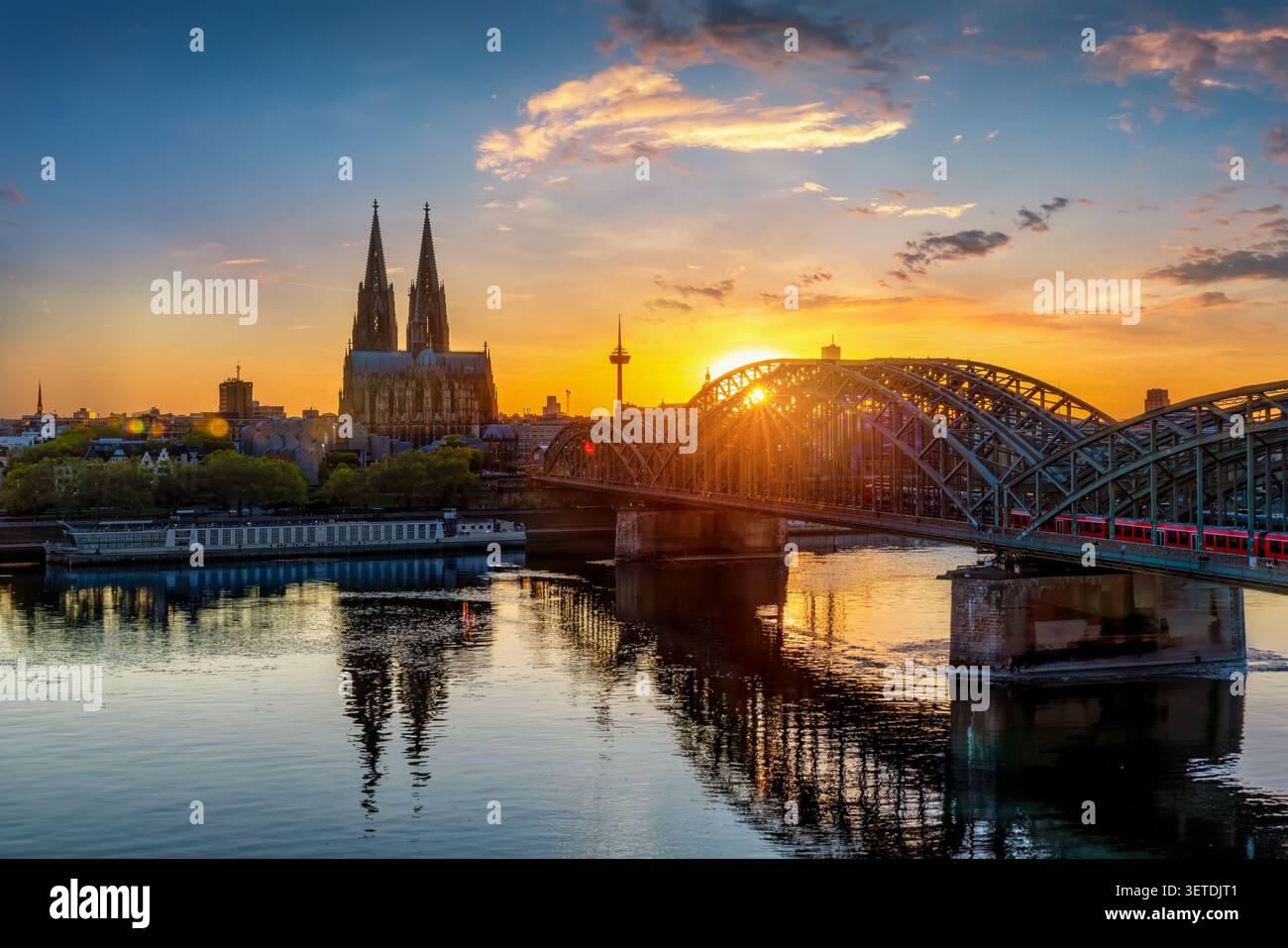 Erhöhter, ruhiger Blick auf den Sonnenuntergang im Sommer auf die Kölner Stadtlandschaft mit Rhein, Hohenzollernbrücke und ikonischem Dom Stockfoto