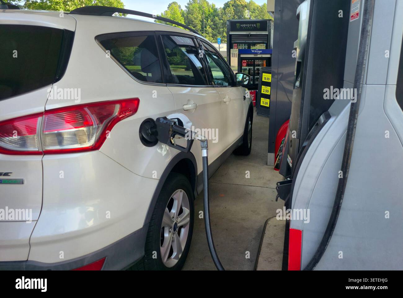 Ein weißer SUV, der an einer Tankstelle in den Vereinigten Staaten betankt wird. Die Marke für Kraftstoffpumpe und Lebensmittelgeschäft ist in einem Kroger-Tankzentrum sichtbar - Smartphone-aufgenommenes Stockfoto