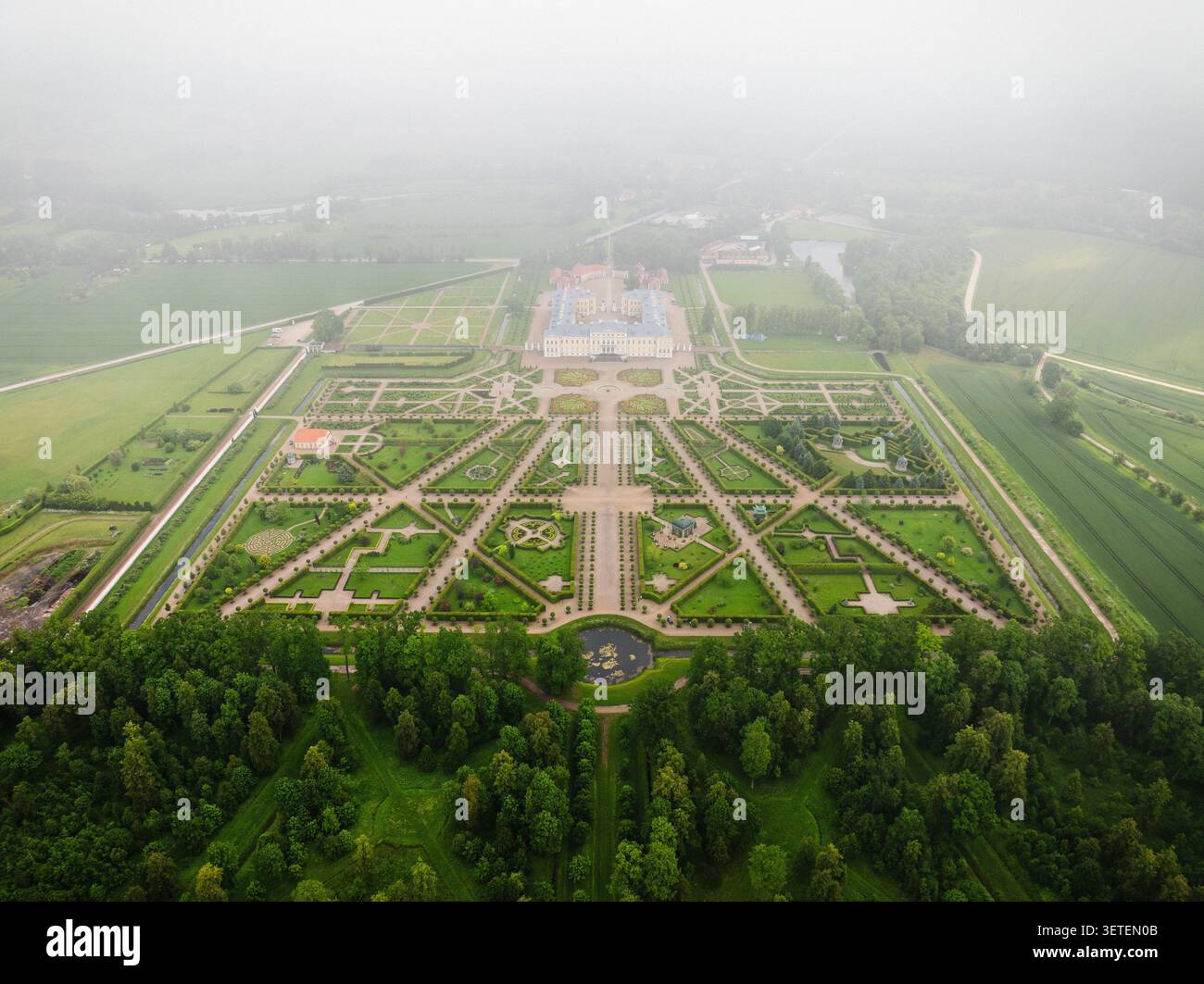 Blick aus der Vogelperspektive auf Schloss Rundale mit symmetrischen barocken Gärten, gepflegten Hecken und Kieswegen umgeben von üppigen Wäldern, Pilsrundale, Bausk Stockfoto