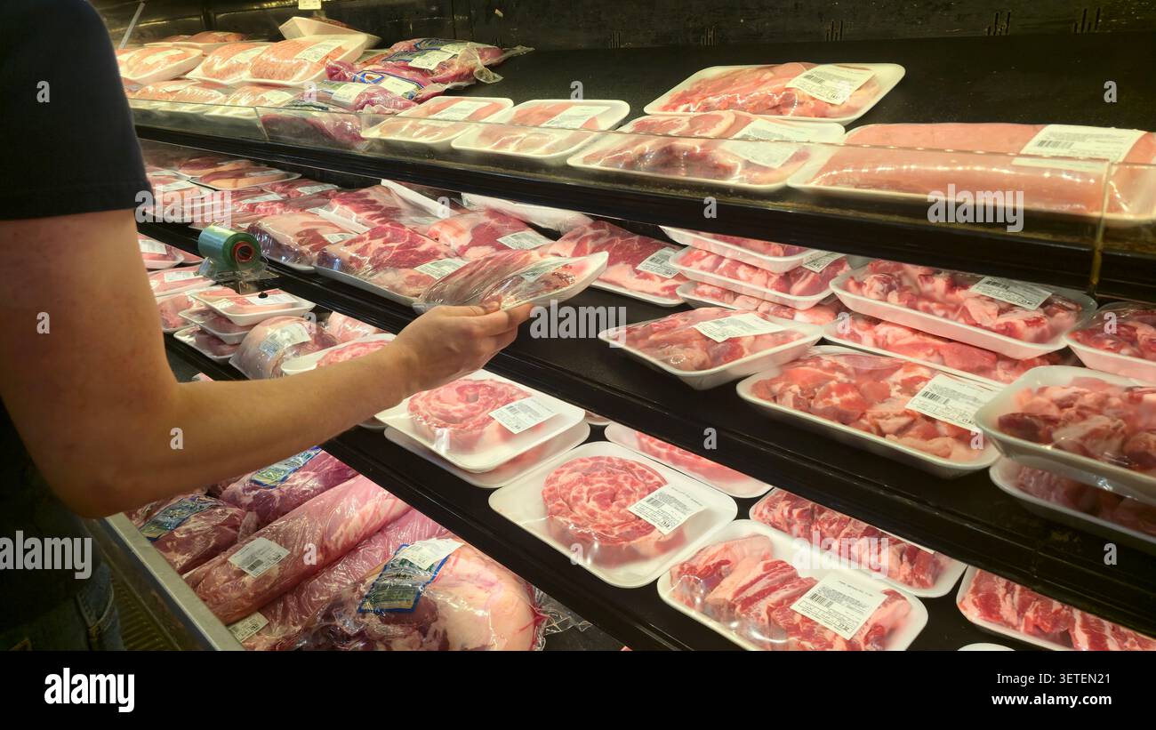 Einkäufer wählt verpacktes Frischfleisch aus der Kühltheke in einem Supermarkt Stockfoto