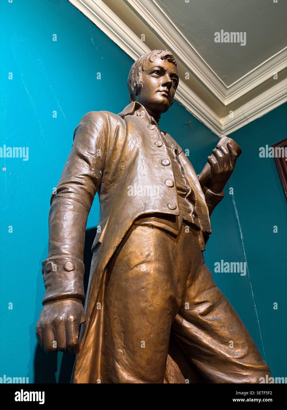 Eine Bronzeskulptur des Dichters Robert Burns im Writers' Museum in Edinburgh, Schottland, vor einer blaugrünen Wand. Stockfoto