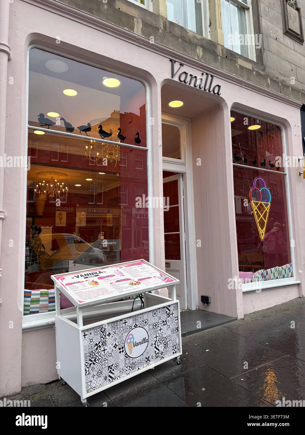 Geschäfte vor dem Vanilla-Eiscafé auf der Royal Mile, High Street, Edinburgh, Schottland. Neon-Eiscreme-Beschilderung und Außenmenüstand. Stockfoto