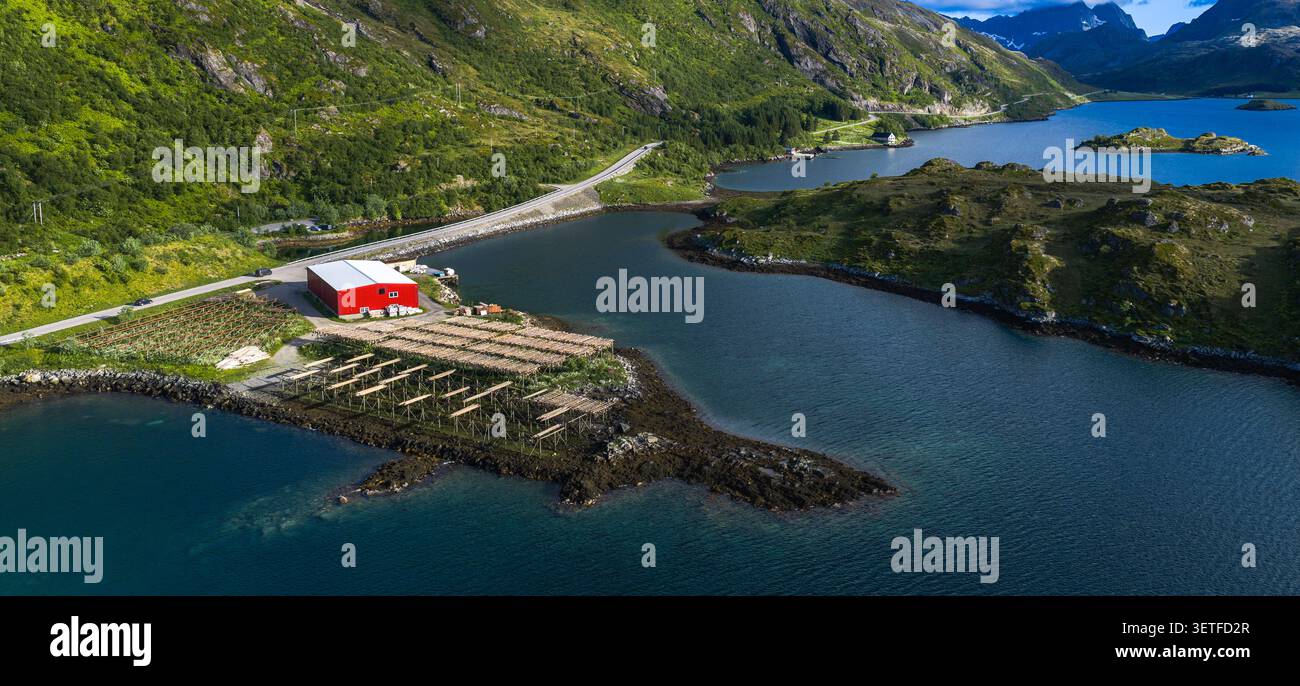 Malerische Aussicht auf eine rote Fischfarm mit Holztrocknern entlang der unberührten Küste der Lofoten Islands, umgeben von Stockfoto