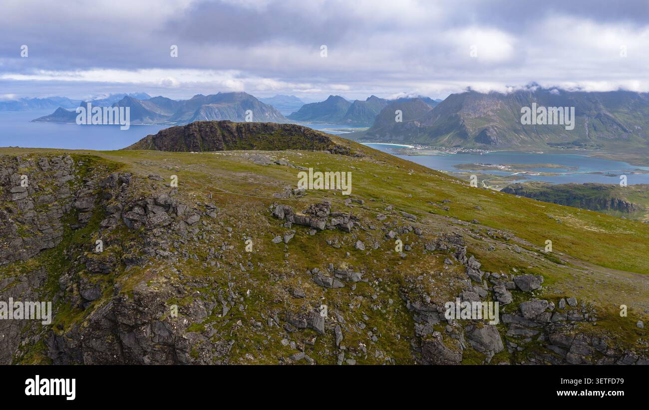 Atemberaubende alpine Landschaft der Lofoten Inseln mit felsigen Gipfeln, grüner Tundra und dramatischen Küstenfjorden mit Bergen und Stockfoto