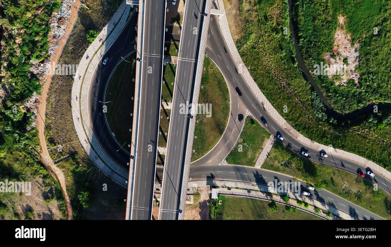 Die Luftaufnahme erfasst komplexe Autobahnkreuze. Mehrere Betonbrücken verbinden Straßen. Fahrzeuge fahren durch kurvenreiche Fahrspuren. Reibungsloser Verkehrsfluss Stockfoto