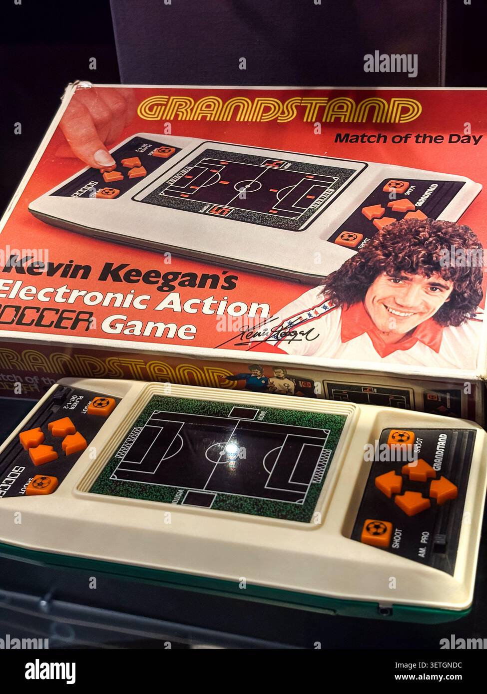 Eine klassische elektronische Handheld-Fußballkonsole für das Spiel des Tages auf der Tribüne mit Originalverpackung. Stockfoto