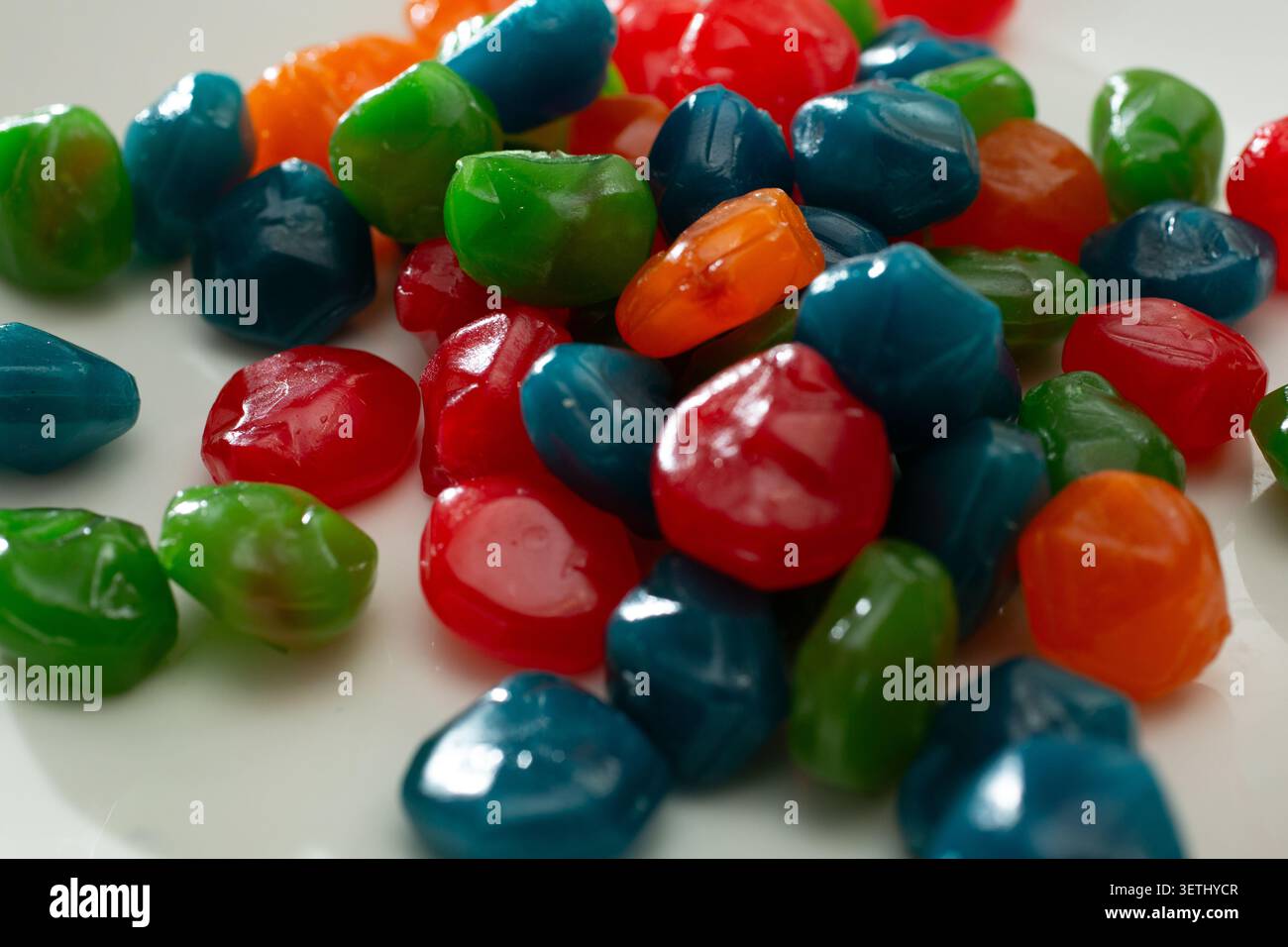 Ein Blick auf einen Haufen saftiger Regenbogenbonbons auf einem Teller. Stockfoto