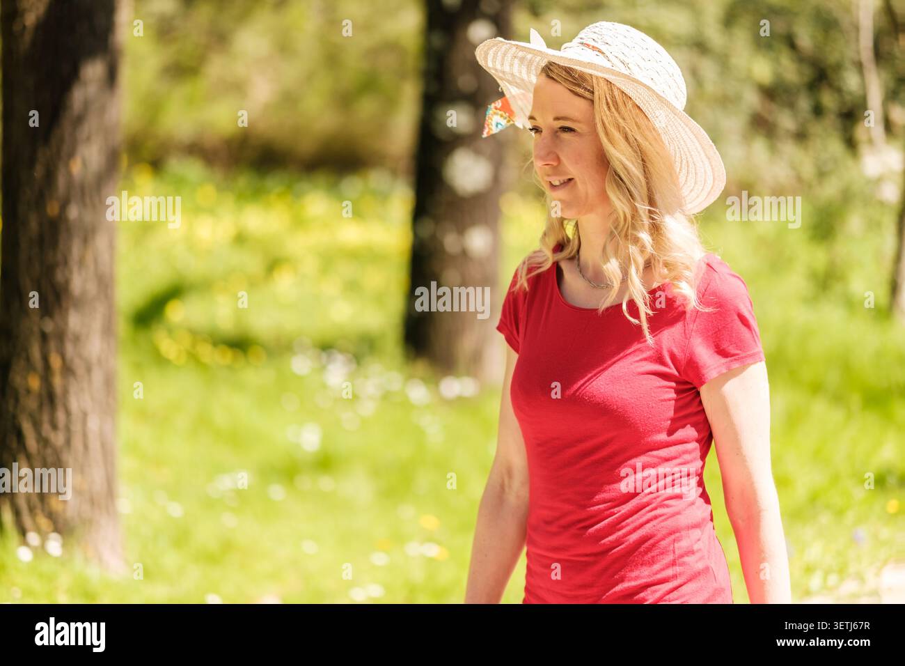 Blonde Frau mit Sonnenhut, die einen sonnigen Tag im Freien genießt Stockfoto