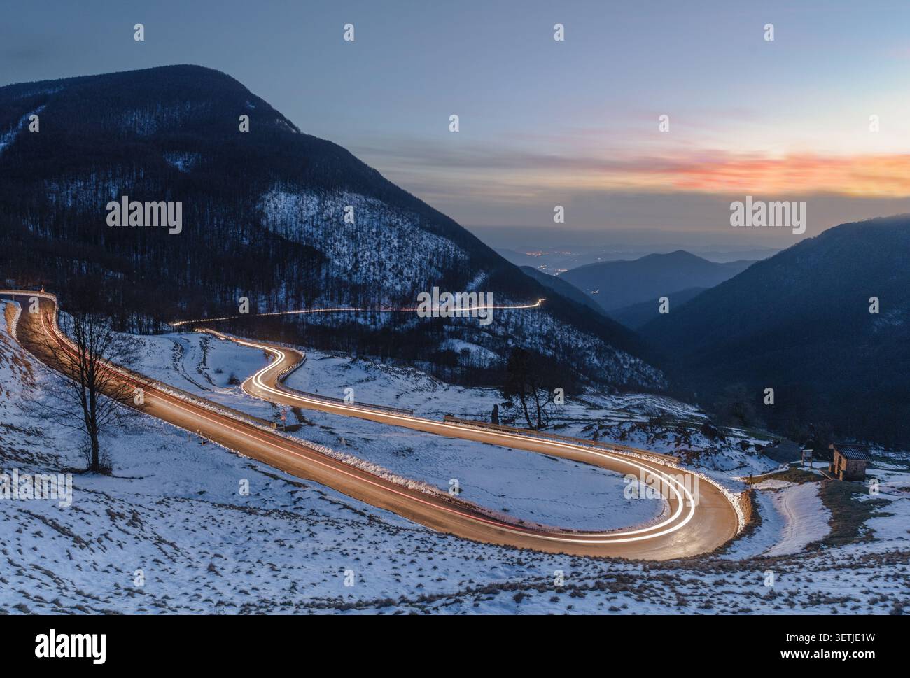 Blick auf eine kurvenreiche Straße mit leichten Autowegen durch die verschneite Landschaft des Parco Nazionale dell'Appennino Tosco-Emiliano in Sassalbo, Provinz di Ma Stockfoto