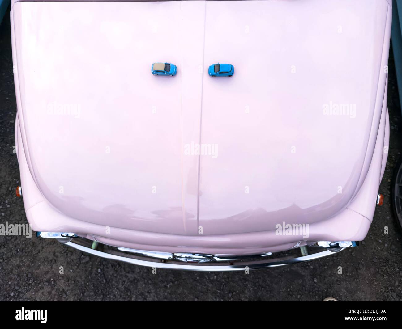 Draufsicht eines rosafarbenen Fiat 500 aus italien mit zwei blauen Fiat 500 Spielzeugen auf der Vorderseite Stockfoto