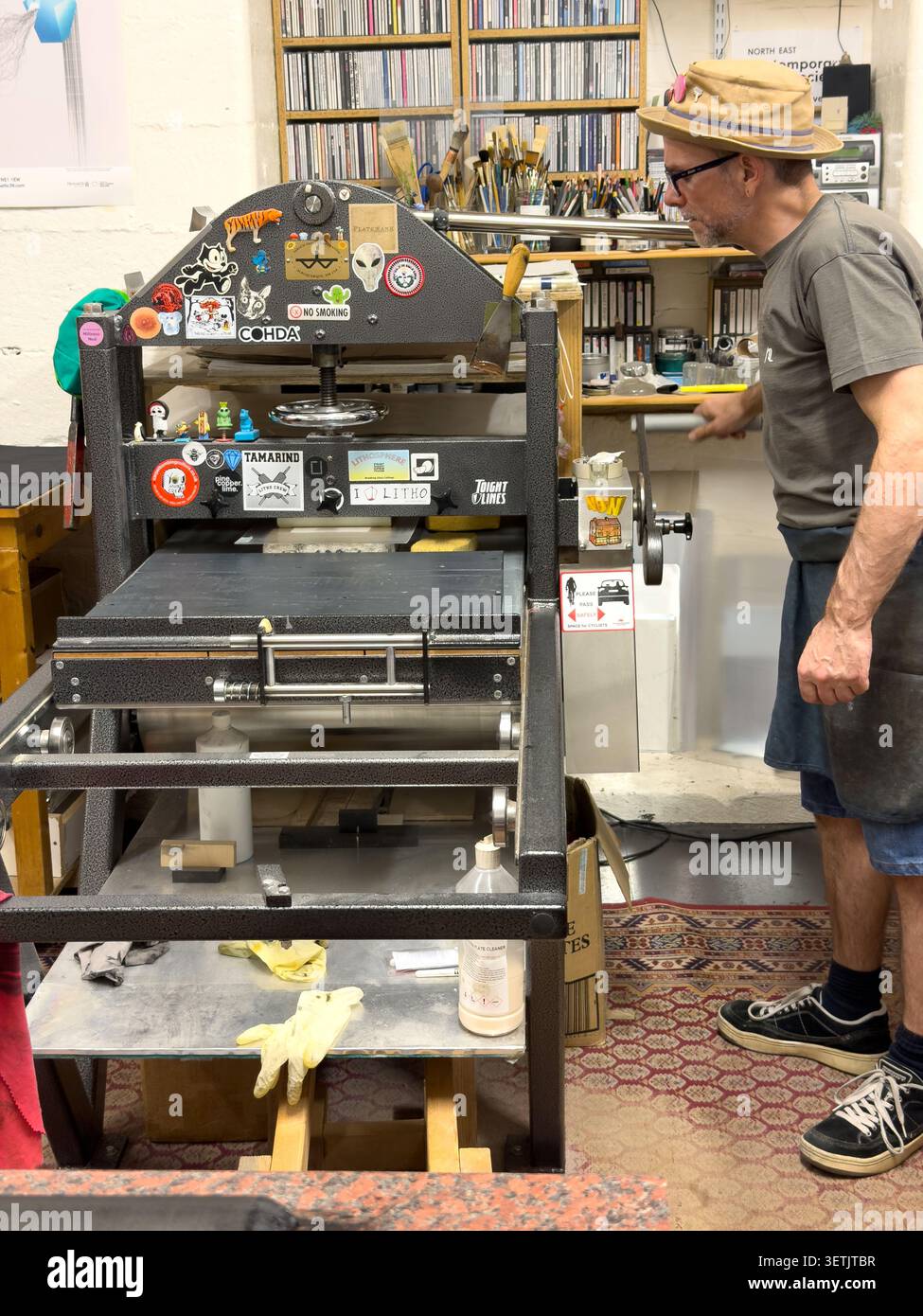 Mann, der eine professionelle Lithografie-Druckmaschine in einem Kunststudio und einer Druckwerkstatt betreibt - Smartphone-aufgenommenes Stockfoto