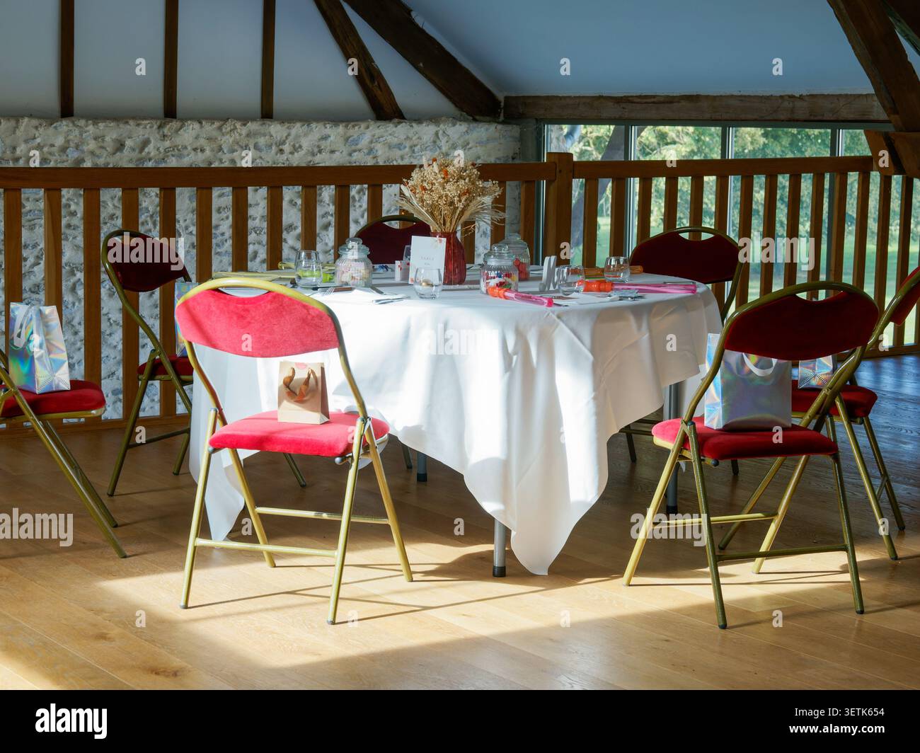 Elegant eingerichteter Rezeptionstisch für Gäste in einem rustikalen Hochzeitsort mit freiliegenden Holzbalken in Frankreich. Stockfoto