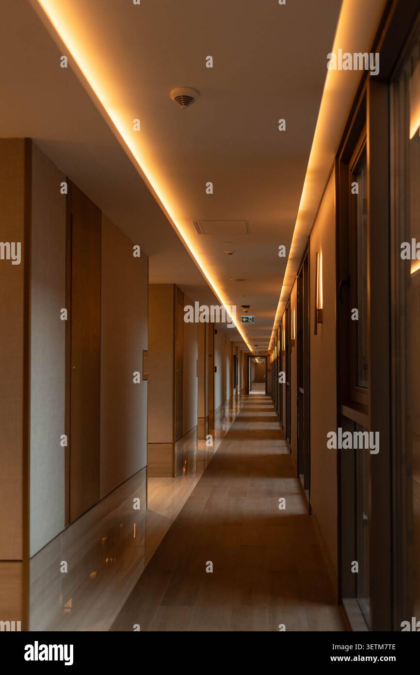 Warm beleuchteter Hotelkorridor mit langer linearer Perspektive und reflektierendem Boden Stockfoto