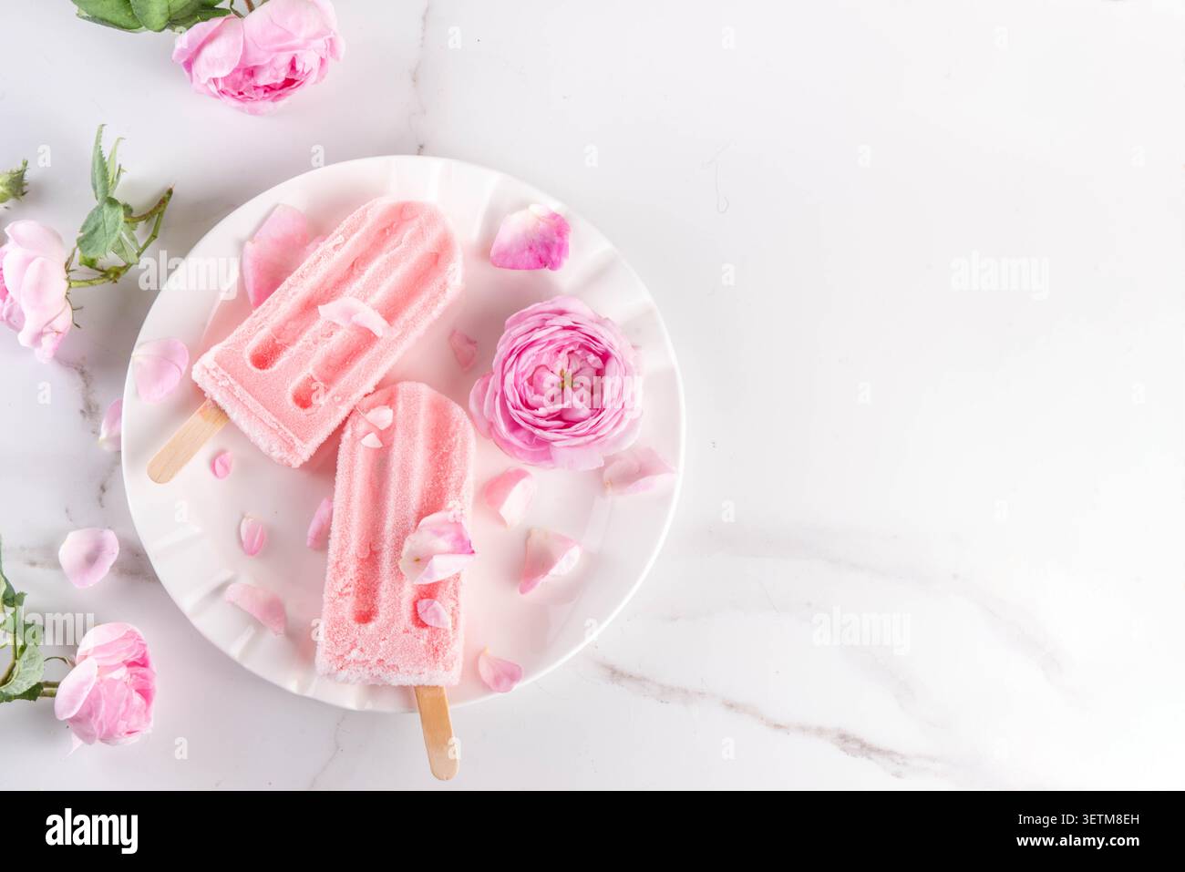 Süße Kräuterrose Eis Lollies in Sticks, leckerer cremiger Tee Rose Blumen gefrorenes Dessert mit Rosenknospen auf weißem Marmor Tisch Backgr Stockfoto