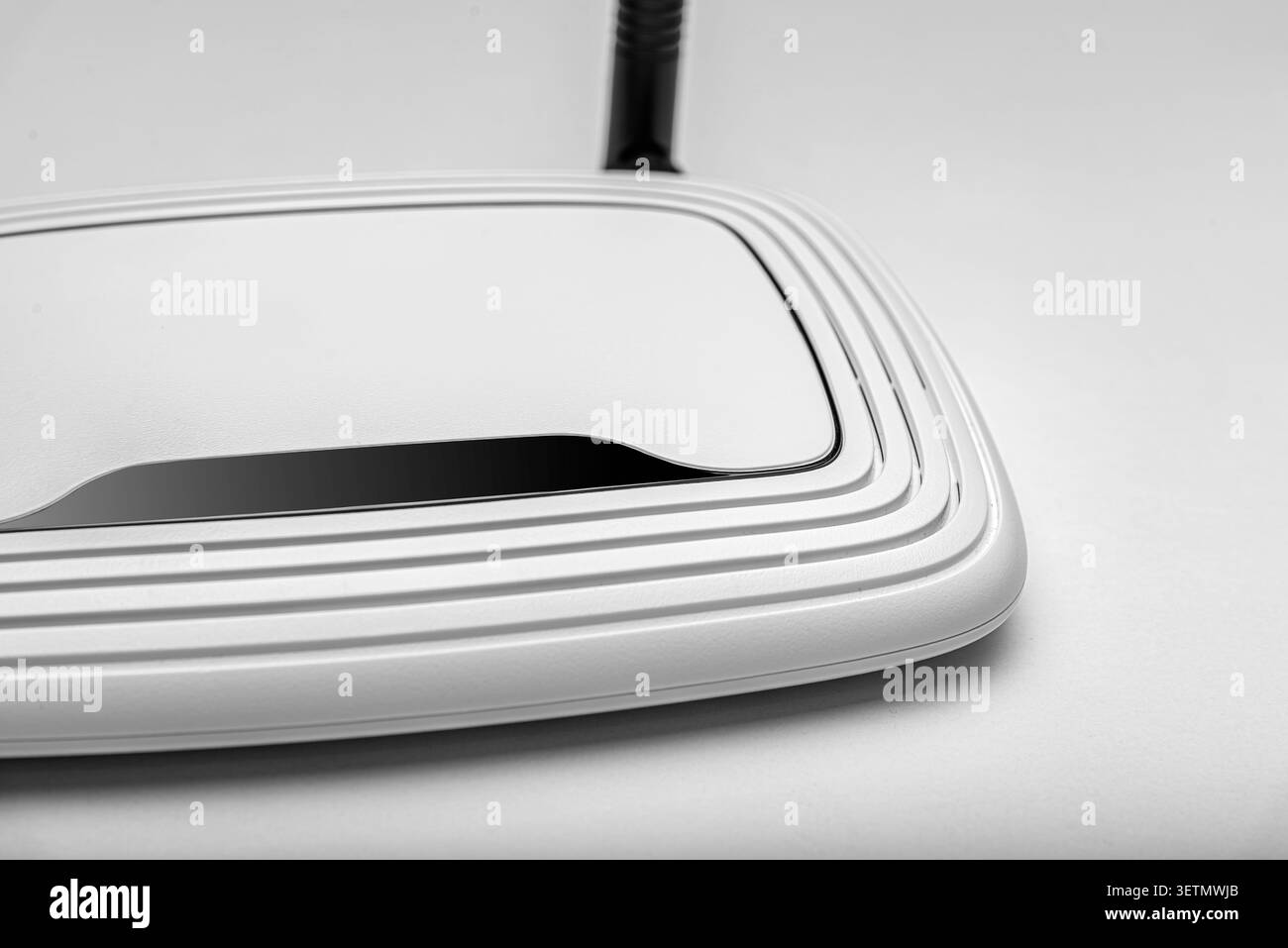 Weißer Wireless-Router mit einer einzelnen Antenne auf einer hellen Oberfläche. Stockfoto