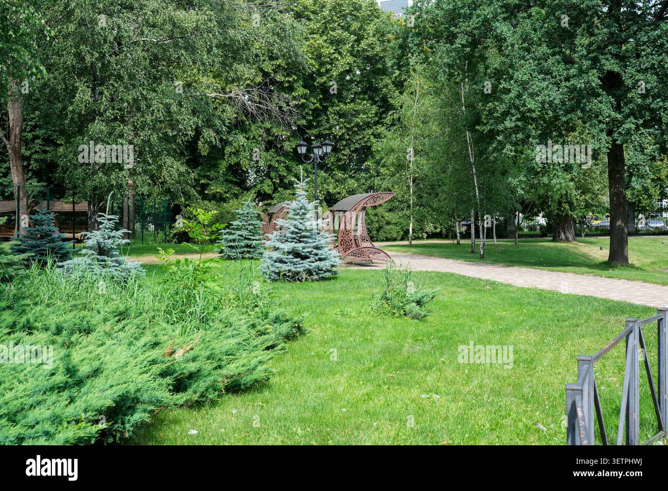 Besucher schlendern durch einen ruhigen Park mit interessanten Kunstwerken und lebendigen Bäumen. Stockfoto