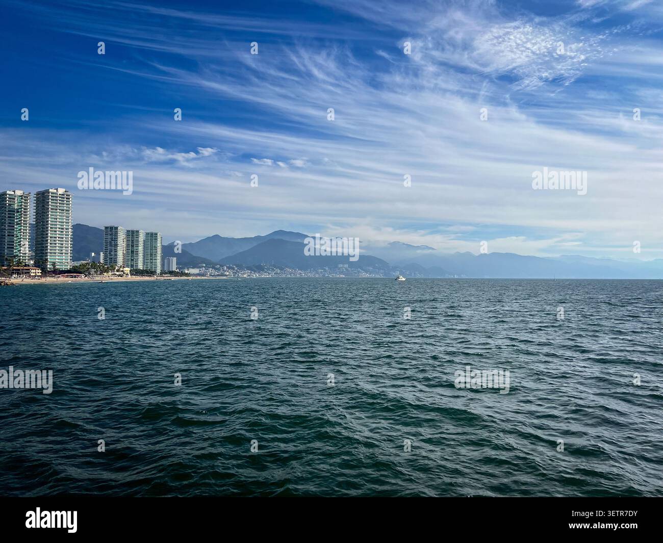 Puerto Vallarta Küste vom Meer aus mit Stadtgebäuden, Strand und Bergen unter blauem Himmel. Stockfoto