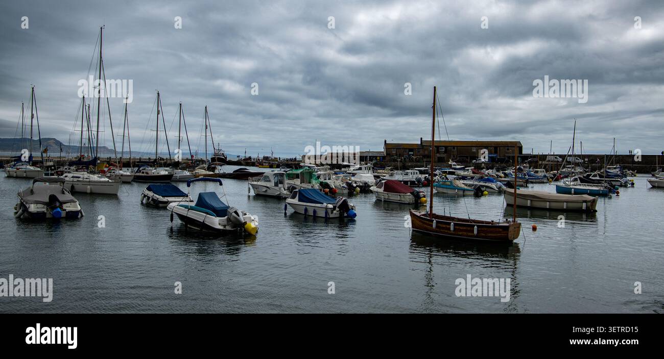 Kleine Boote und Yachten, die an einem bewölkten Tag in einem ruhigen Hafen liegen, Lyme Regis Dorset Stockfoto