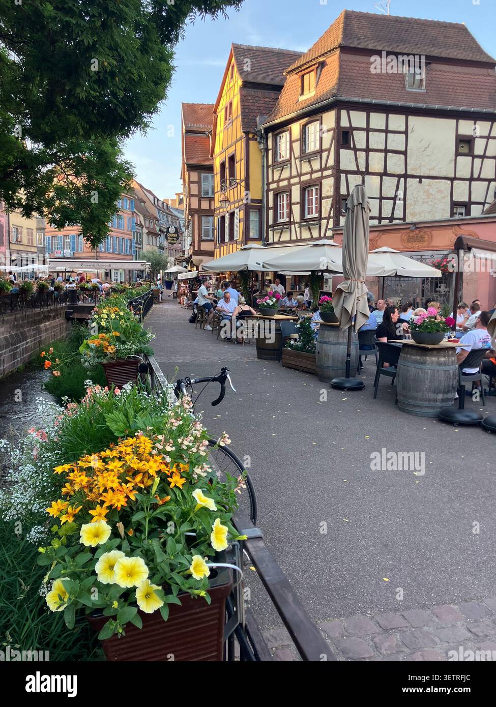 Fachwerkgebäude und Restaurantterrassen entlang des Kanals am Place de l'Ancienne Douane, Colmar, Haut-Rhin, Frankreich - Smartphone-aufgenommenes Stockfoto