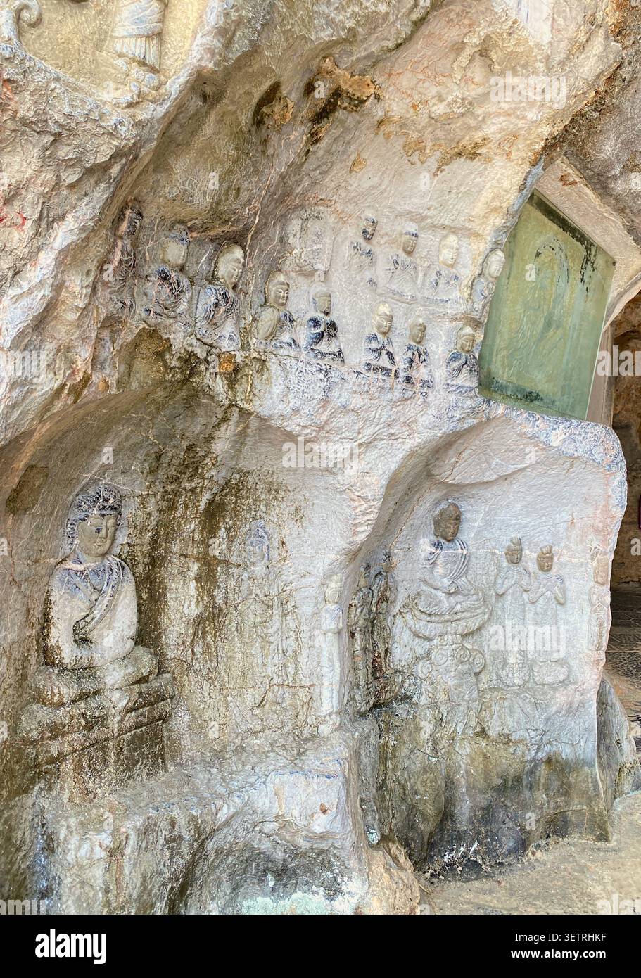 Antike buddhistische Reliefstatuen und Votivfiguren, die direkt in eine Kalksteingrotte in Guangxi, China, geschnitzt wurden - Smartphone-aufgenommenes Stockfoto