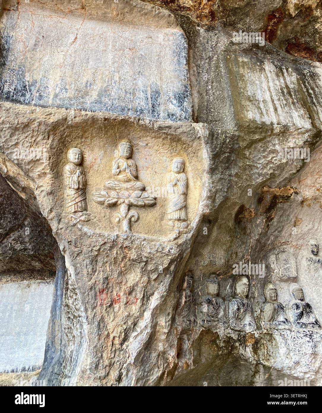 Historische chinesische Kalligraphie-Textinschriften auf Stein neben einer geschnitzten Buddha-Lotus-Triade in Guangxi, China - Smartphone-aufgenommenes Stockfoto