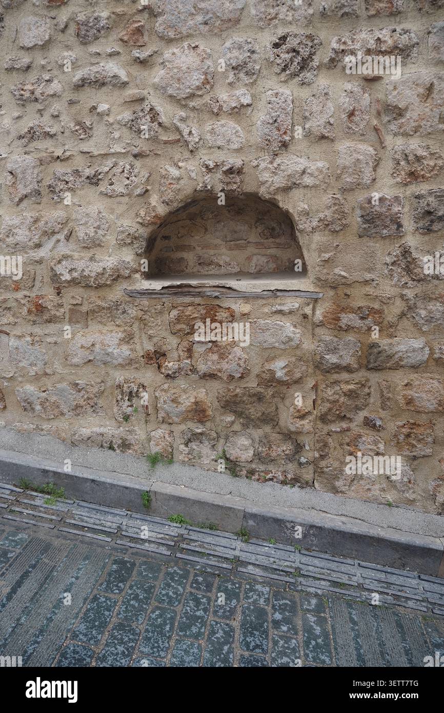Alte Steinmauer mit einem kleinen Fenster in einer Stadtstraße Stockfoto