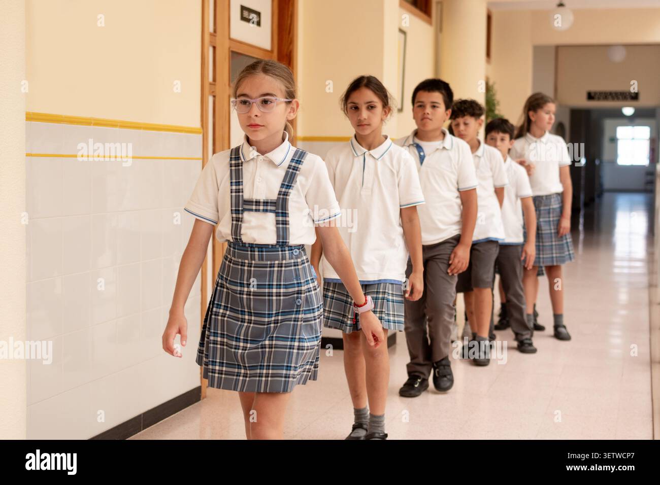 Gruppe von Grundschulschülern, die in einer geordneten Linie durch einen Schulkorridor laufen. Schüler, Schüler, Schule, Schulkinder, Kind, Kinder, c Stockfoto