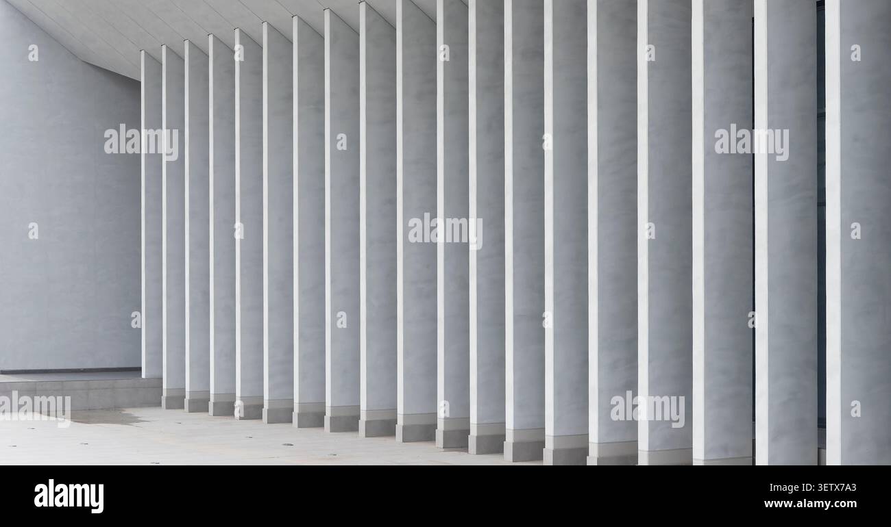 Innenarchitektur mit Betonsäulen, die eine geometrische Perspektive schaffen. Minimale Struktur mit sich wiederholenden vertikalen Elementen, die Rhythmus bilden. Stockfoto