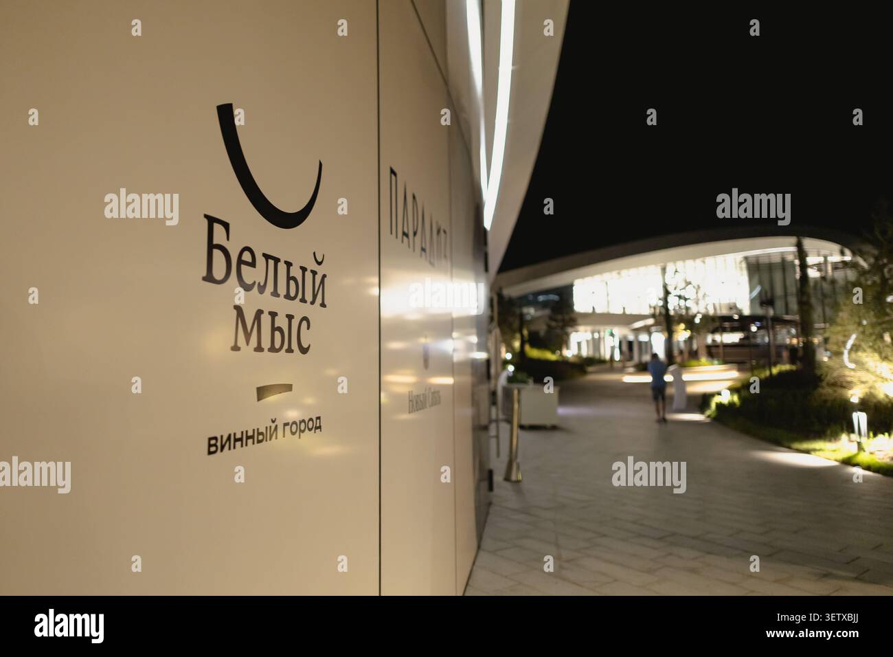 Gelendschik, Russland - 14. Juni 2026: Eröffnung der Weinstadt Weißkap. Nahaufnahme der beleuchteten weißen Wand mit schwarzem russischem Textlogo bei Nacht. Stockfoto