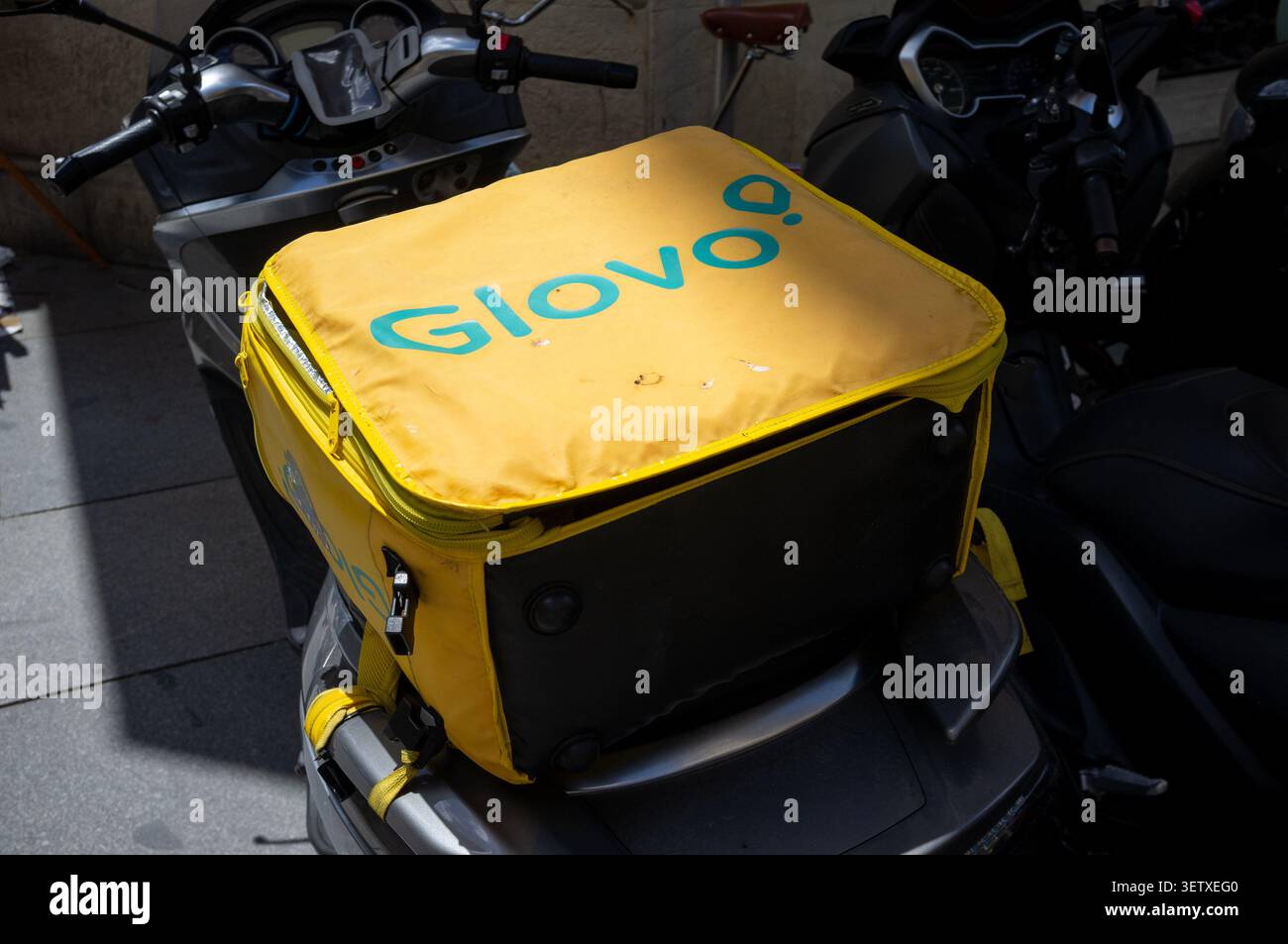 Glovo ist ein spanisches On-Demand-Lieferunternehmen, das in Sevilla, Spanien, eine Tasche auf der Rückseite eines Lieferrads abgebildet ist. Stockfoto