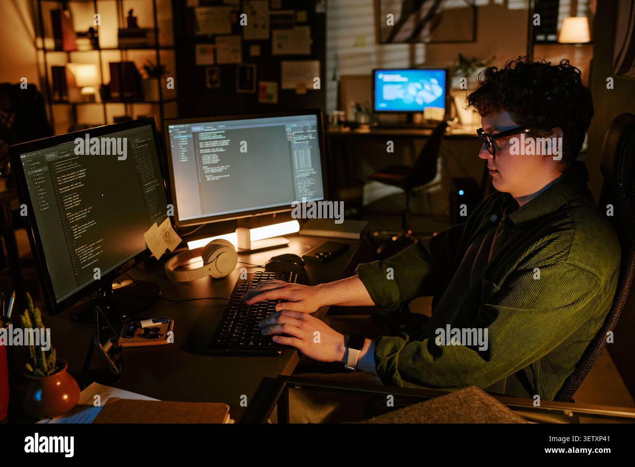 Kodierung für Erwachsene bei zwei Monitoren im Büro bei Nacht Stockfoto