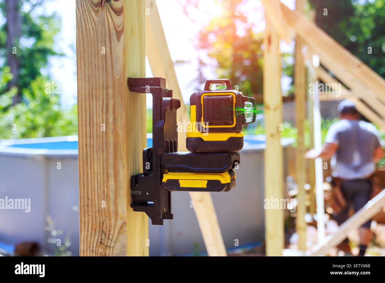 Der Arbeiter stellt auf der Baustelle ein Laser-Level-Werkzeug auf Holzstrahl auf, um die Messungen zu überprüfen. Stockfoto