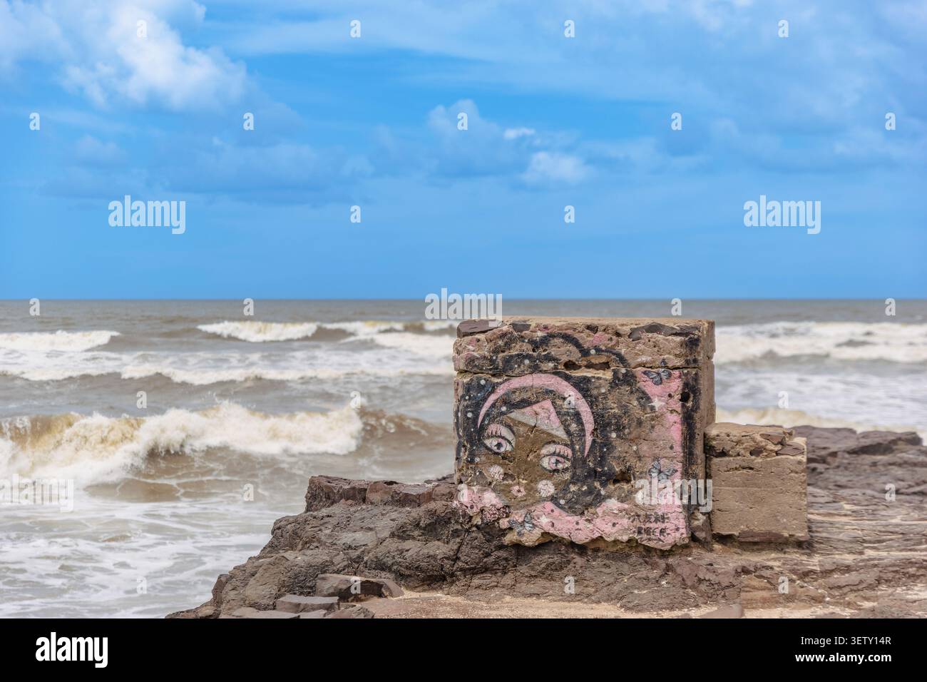 TORRES, BRASILIEN - 25. JANUAR 2024: Straßenkunst-Graffiti eines weiblichen Gesichts, das auf einem Betonblock entlang der felsigen Küste von Torres Beach gemalt ist, mit Ozean Stockfoto