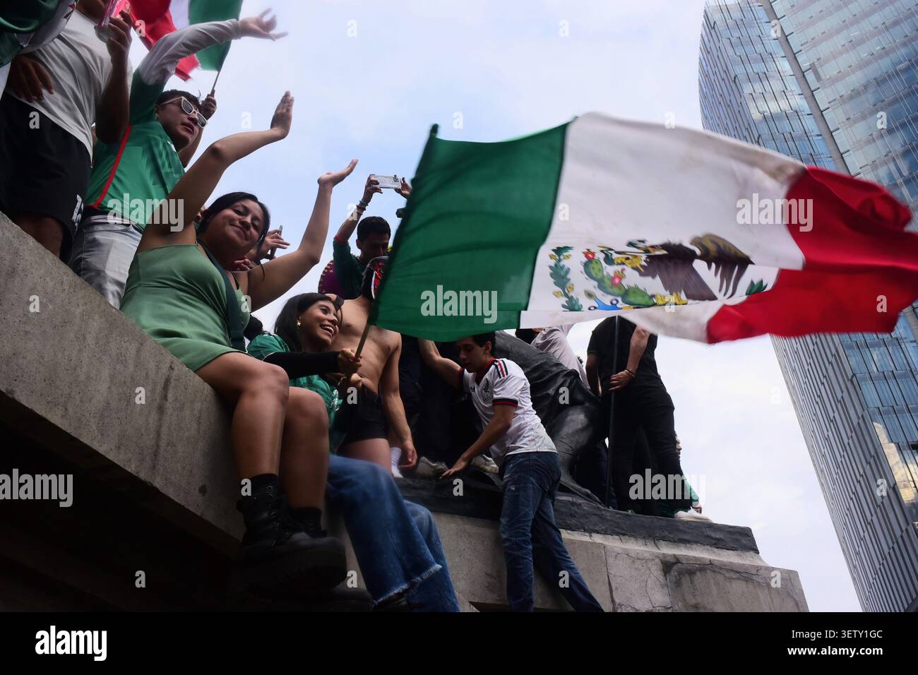 Mexikanische Fans klettern während der WM auf die Statuen des Engels der Unabhängigkeit und schwenken Flaggen. Stockfoto