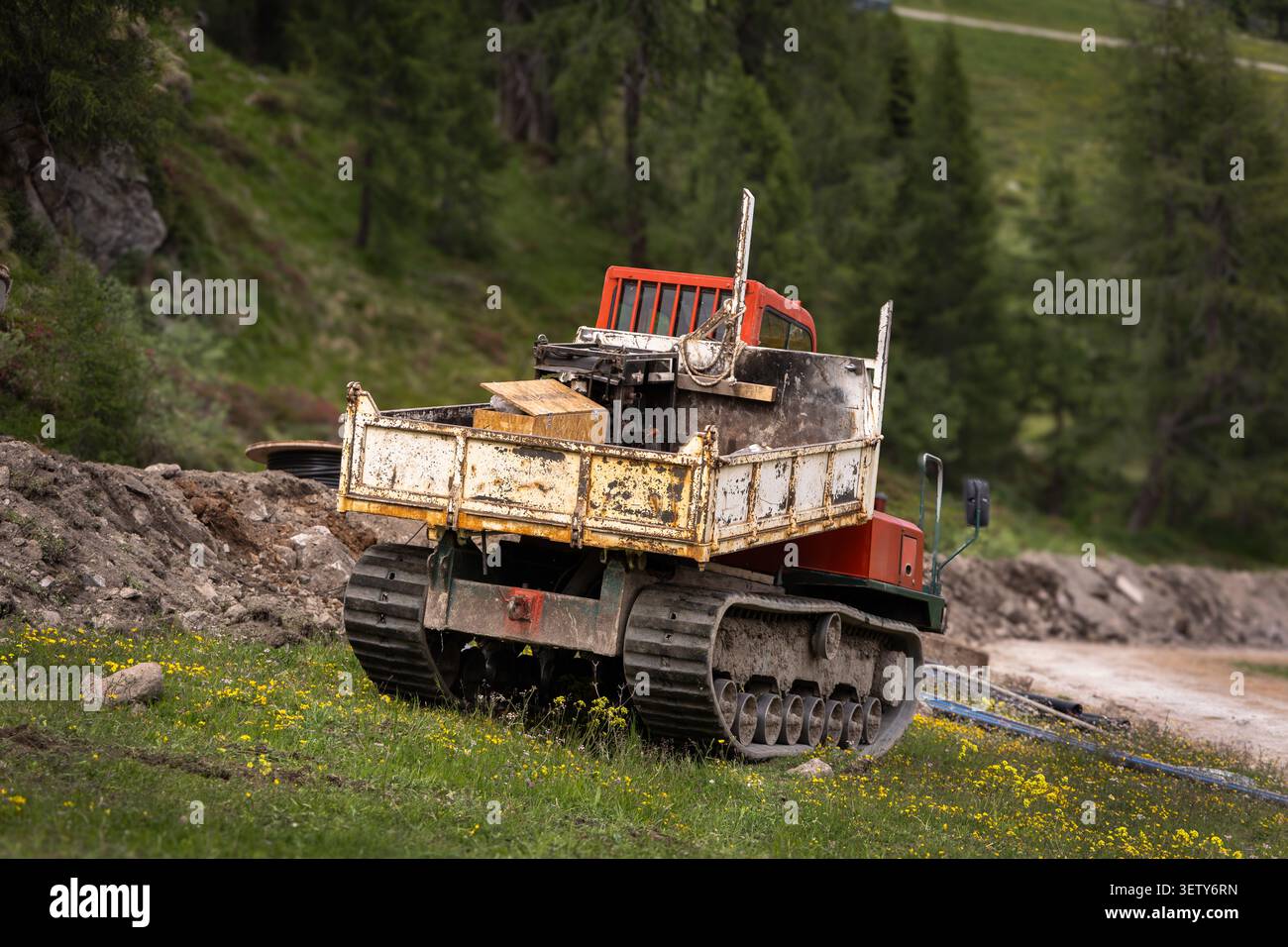 Raupenbaufahrzeug auf einer alpinen Baustelle in den Dolomiten, Norditalien. Stockfoto