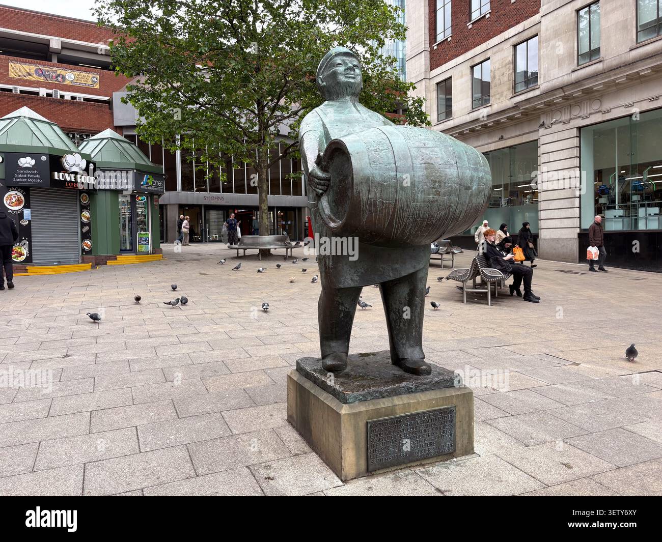 Bronzeskulptur eines Brauers mit einem Bierfass auf dem Dortmund Square, Leeds, Großbritannien, umgeben von einem öffentlichen platz und städtischen Geschäften. Stockfoto