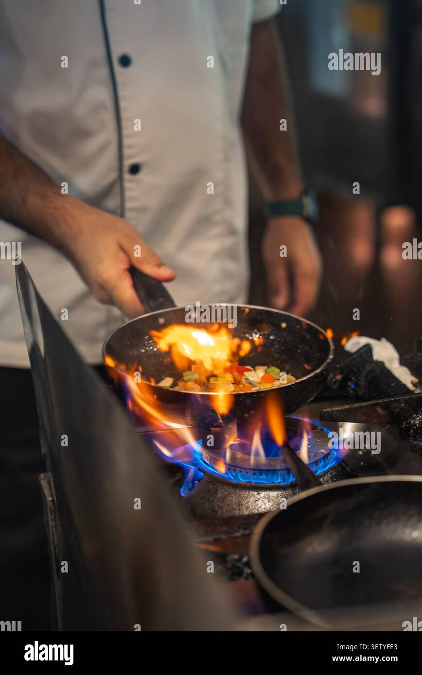 Der Koch sautiert Gemüse über Gasflamme in der Hotelküche der Malediven Stockfoto