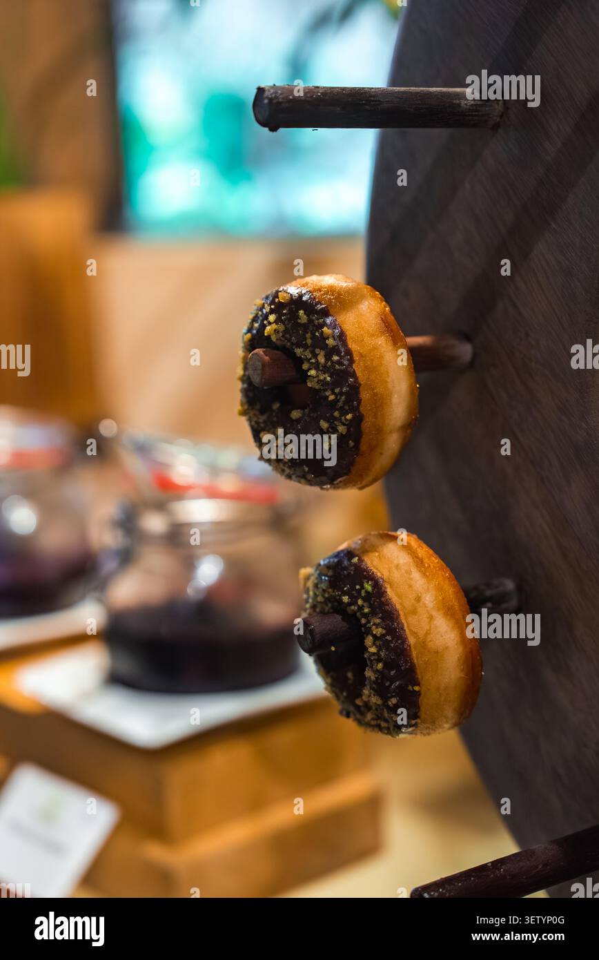 Schokoladenglasierte Donuts mit Nüssen auf dunkler hölzerner Donutwand, Malediven Stockfoto