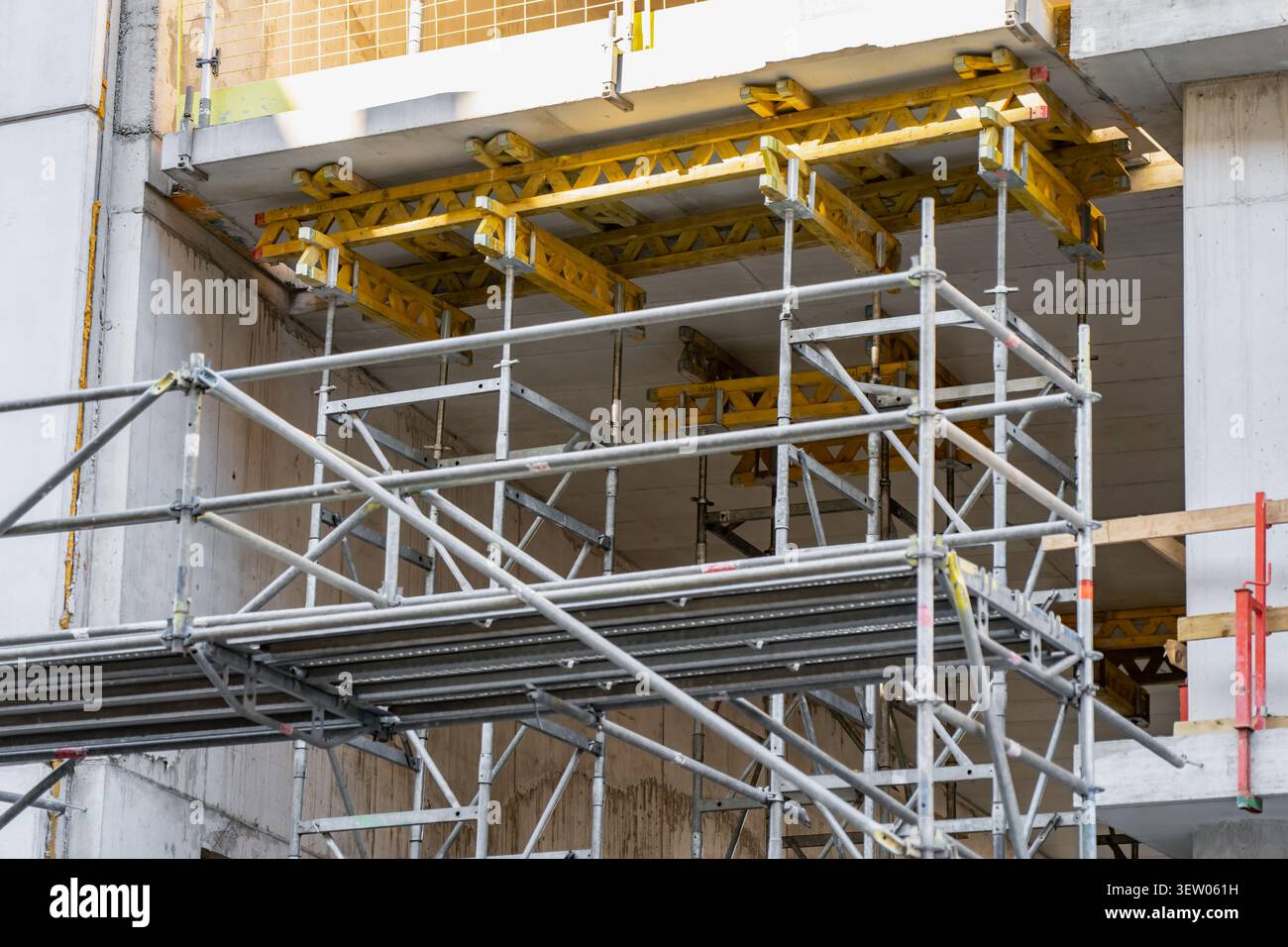 Gerüstrahmen aus Metall, die temporäre gelbe Holzbalken für das Gießen und Aushärten von Beton in einer städtischen Bauzone unterstützen Stockfoto