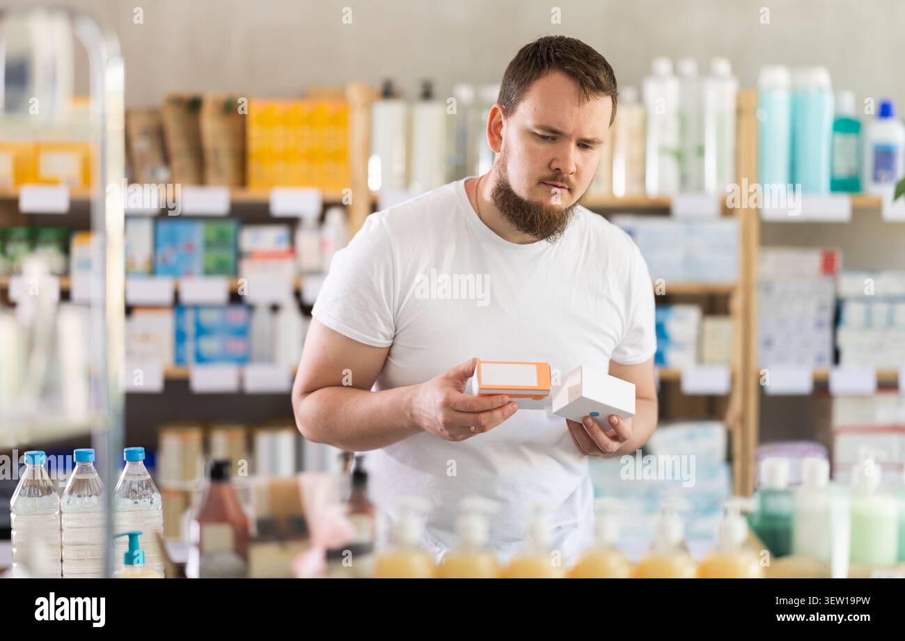 Junger Mann wählt Pillen in der Apotheke Stockfoto