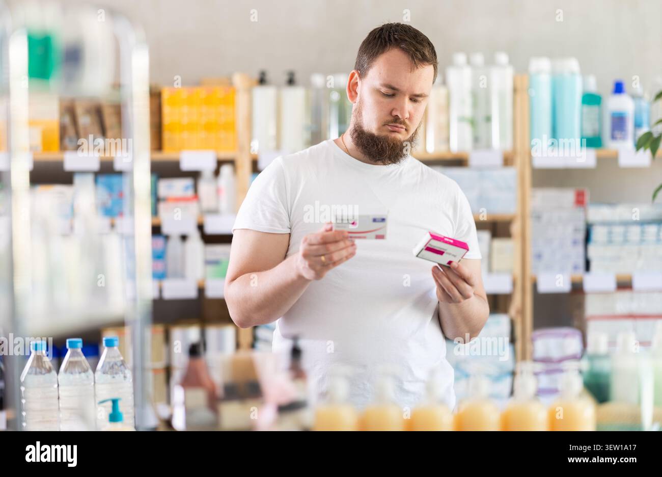 Junger Mann wählt Paracetamol in der Apotheke Stockfoto