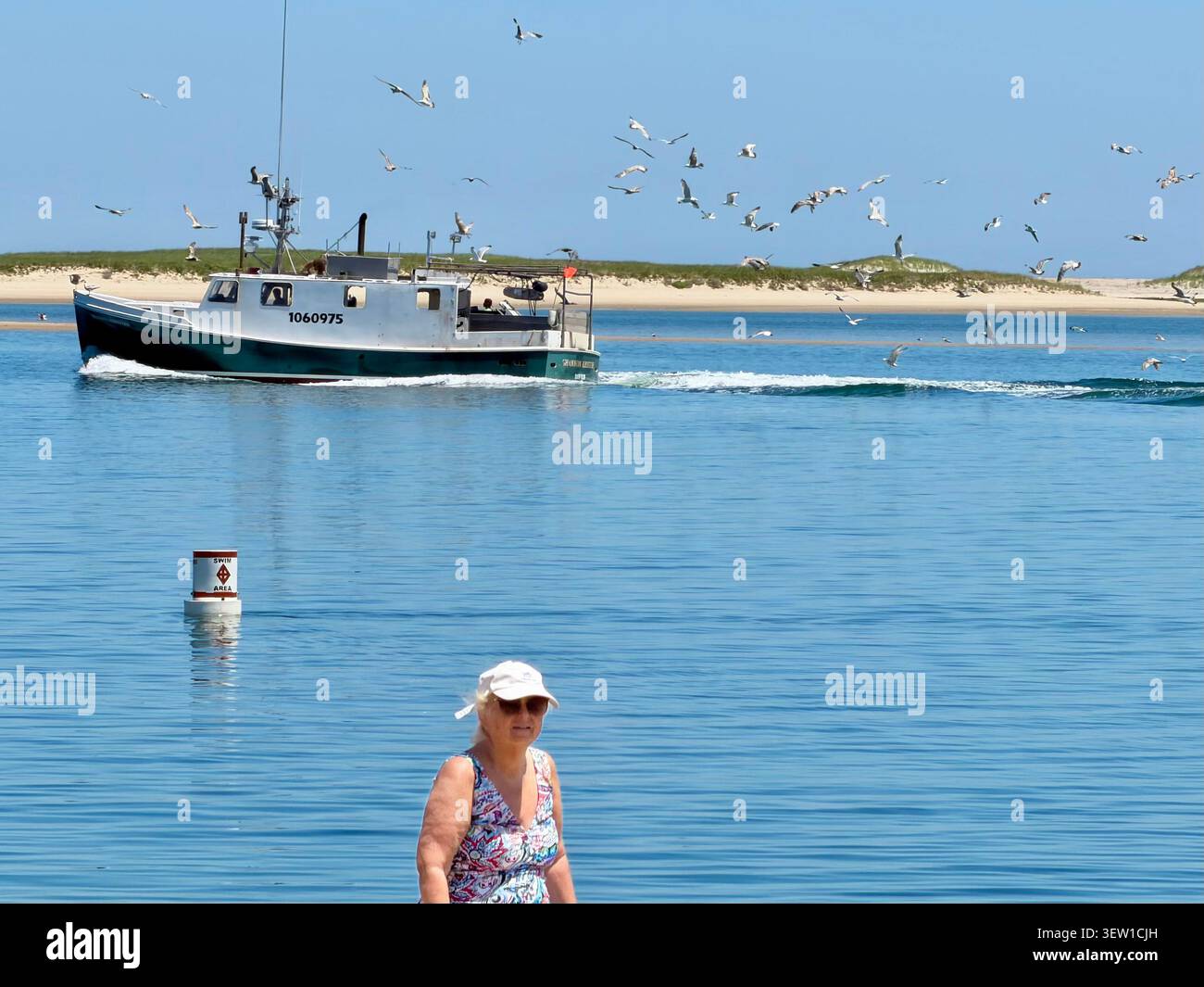 Vom Chatham Light Beach aus gesehen, einem Fischerboot, gefolgt von Möwen, geht es zum Hafen in Chatham, Cape Cod, Massachusetts. North Beach Island hinten. - Smartphone-aufgenommenes Stockfoto