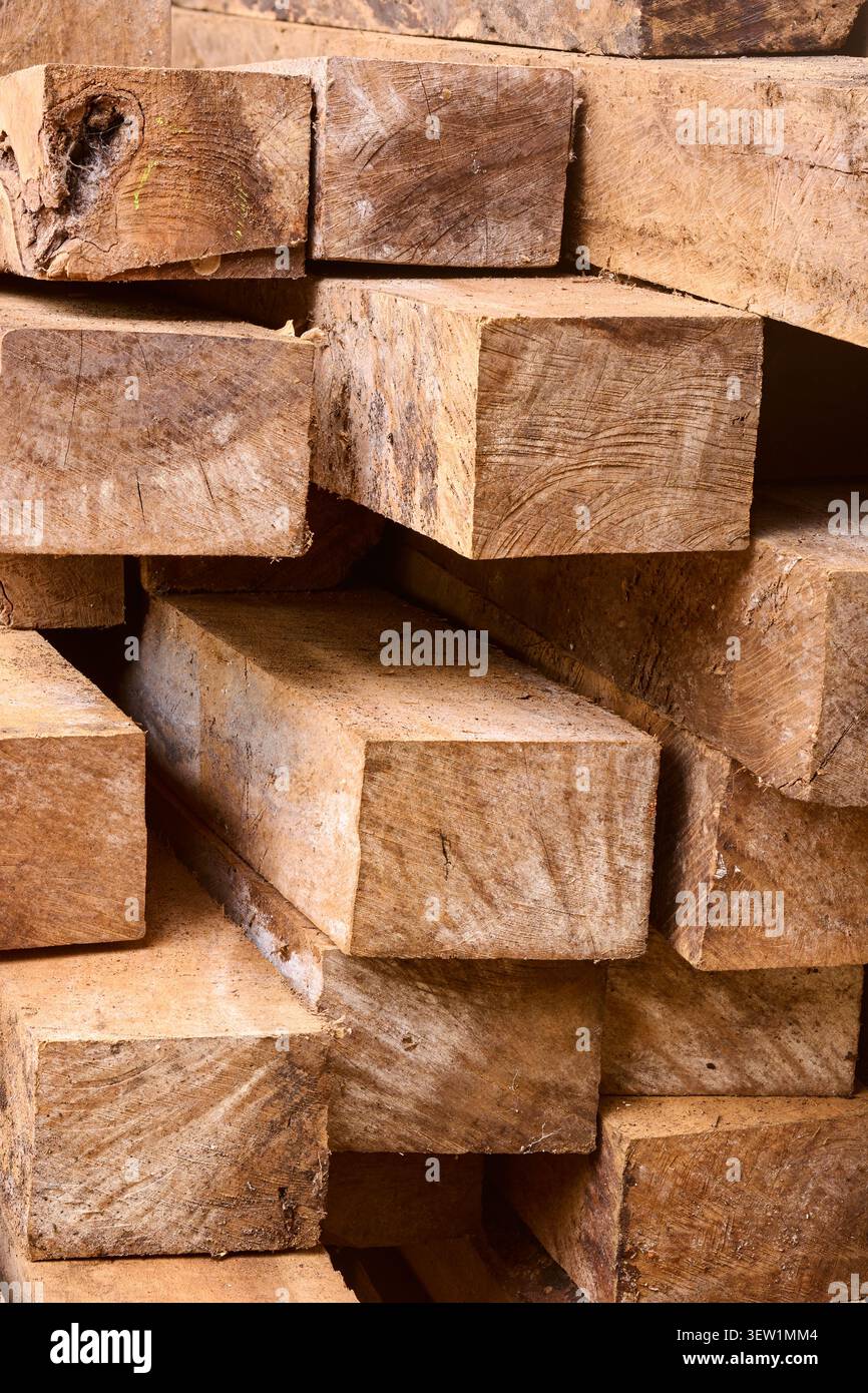Gestapelte quadratische Holzbalken in Nahaufnahme, rohes braunes Holz mit rauer Körnung und Sägemarkierungen, Vollrahmen-Hintergrundstruktur der Baumaterialien Stockfoto