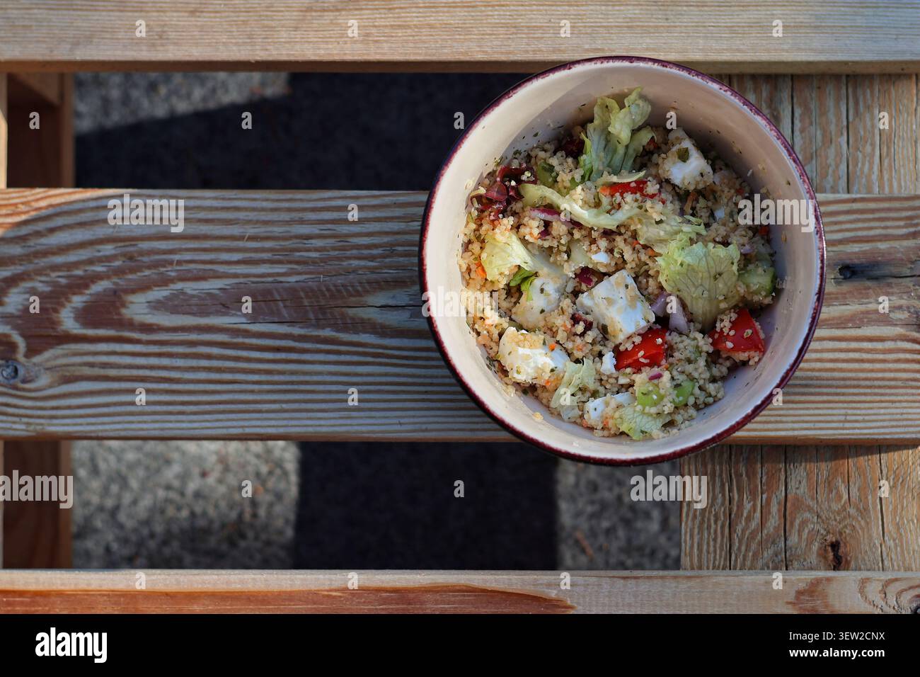 Frischer mediterraner Couscous-Salat mit Fetakäse in Schüssel auf Holztisch Stockfoto