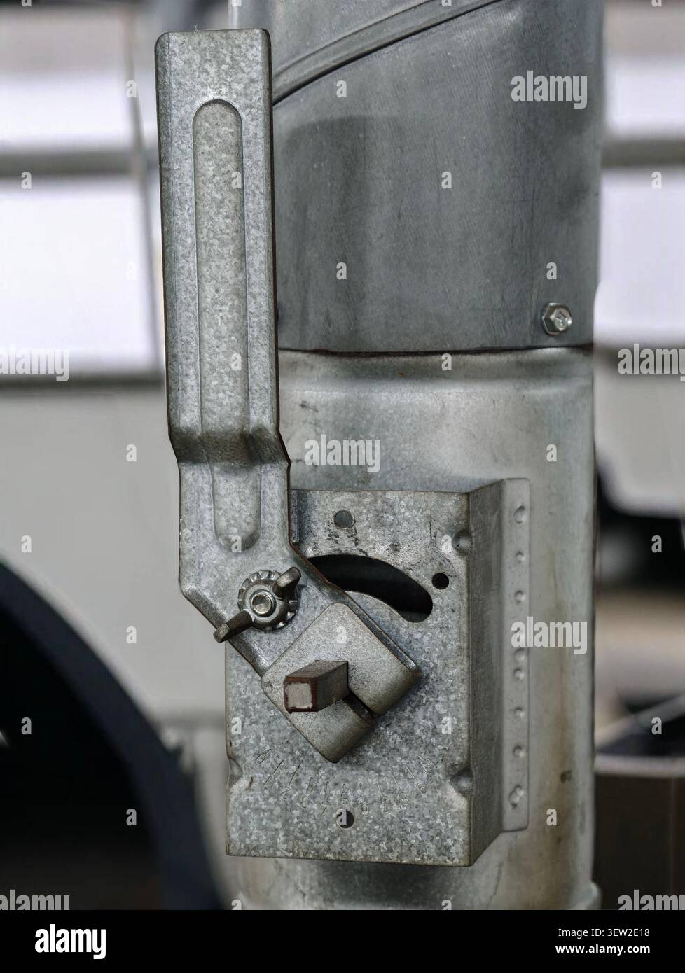 Detaillierte Detailansicht der verzinkten Metallverriegelung und Scharnierbaugruppe, die an einem vertikalen Pfosten montiert sind, mit texturierter Zinkoberfläche, Nieten, Mutter, Flügelmutter und Adjus Stockfoto