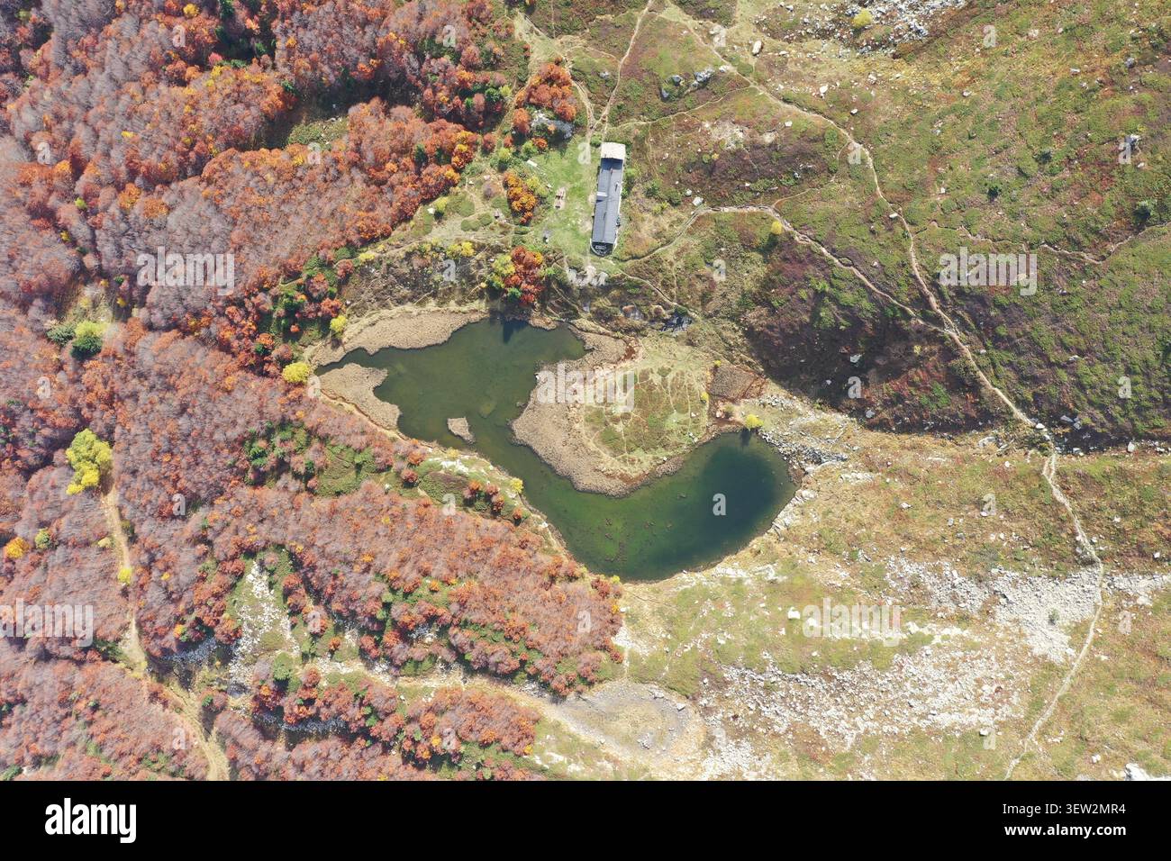 Blick aus der Vogelperspektive auf den Lago Nero, umgeben von Herbstlaub, felsigem Gelände und Bergpfaden in Abetone Cutigliano, Toskana, Italien. Stockfoto