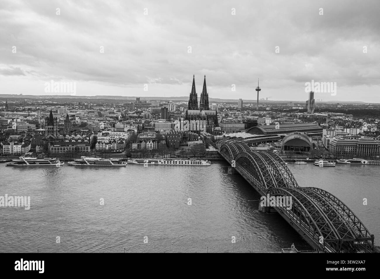 Hohe Winkel-Schwarzweiß-Luftaufnahme des Kölner Doms und der Hohenzollernbrücke, die den Rhein in Köln, Deutschland, überspannt. Stockfoto