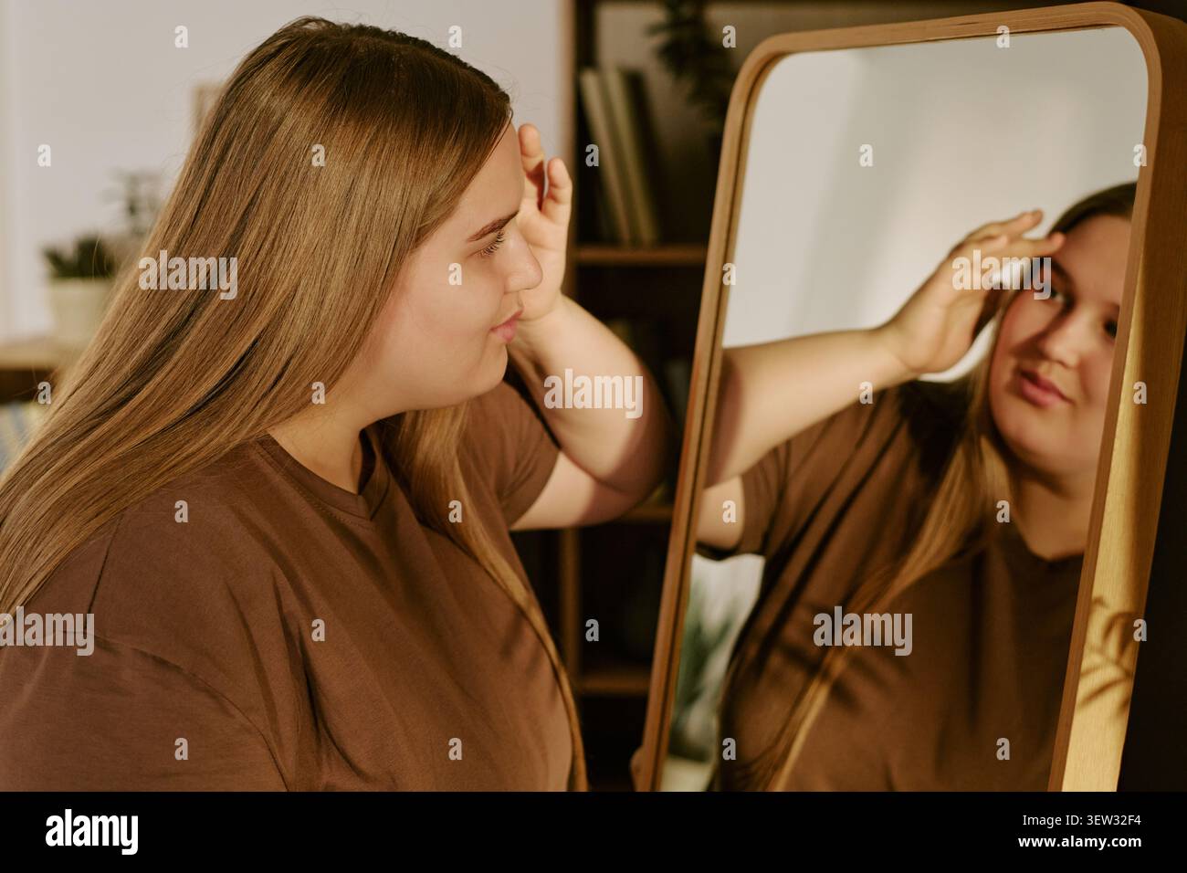 Frau in Übergröße, die im Spiegel für Selbstakzeptanzkampagne sucht Stockfoto